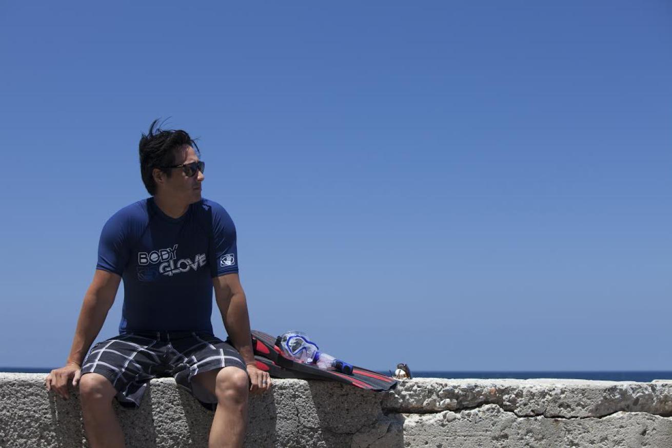 Diver sitting on wall by beach