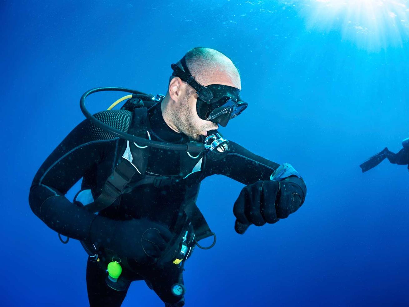 Diver underwater looking at dive computer FAQ