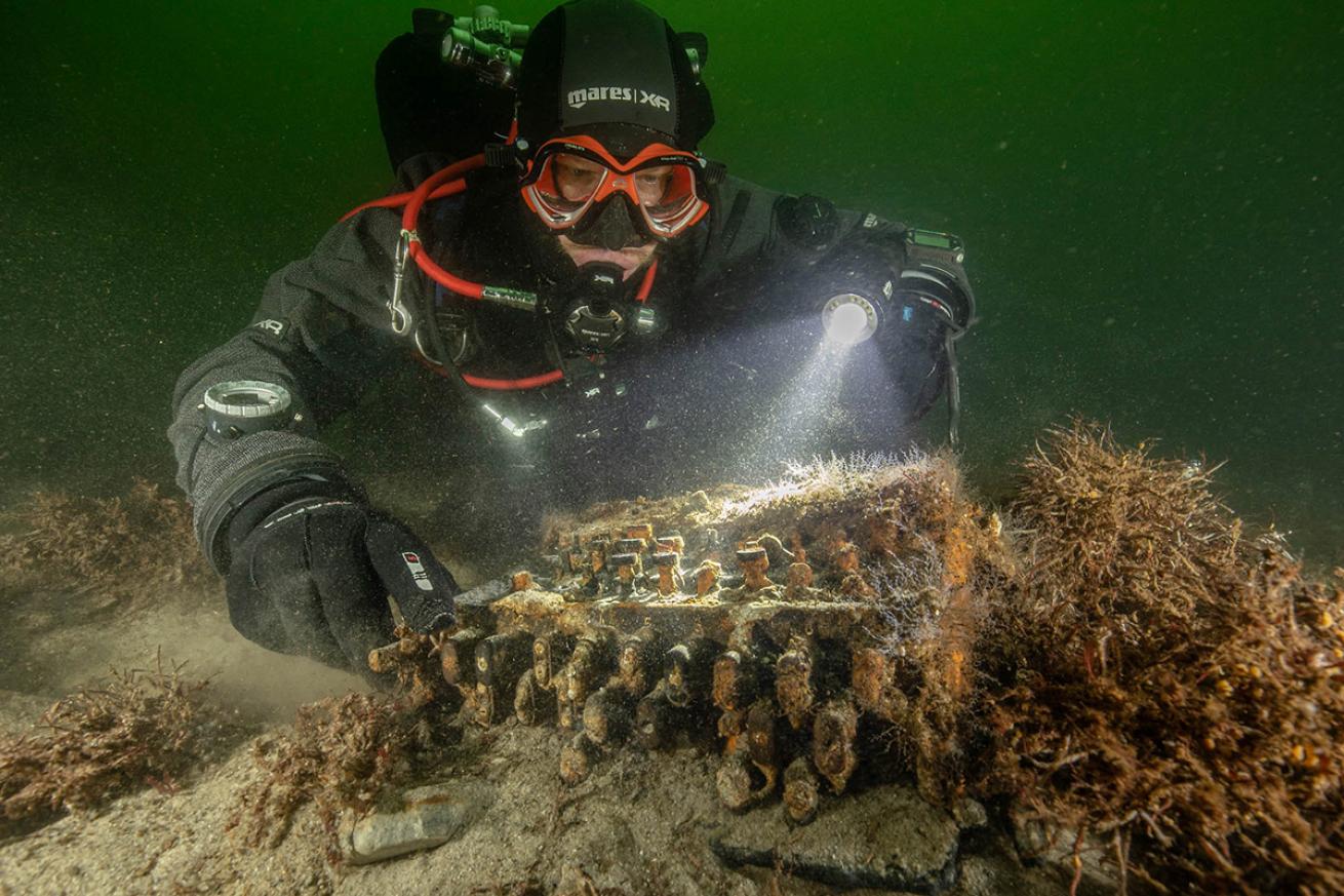 A diver hovers over the newly discovered Enigma machine in the Baltic Sea.