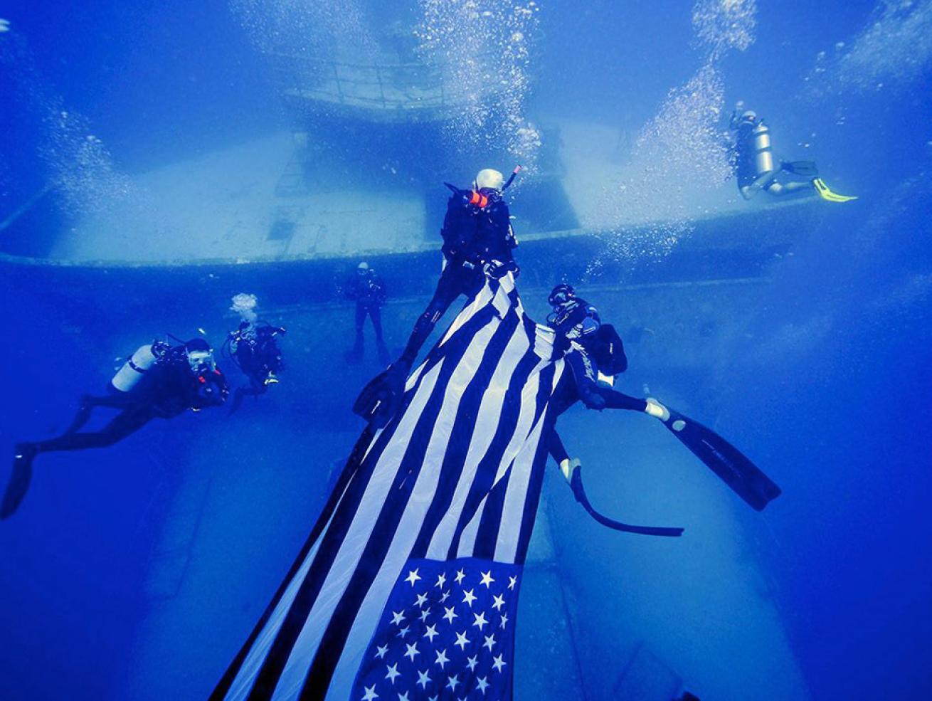 Divers carrying flag near shipwreck