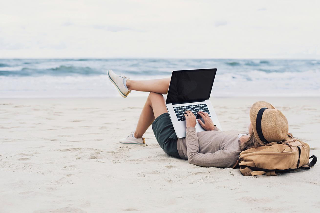 Woman uses laptop on beach