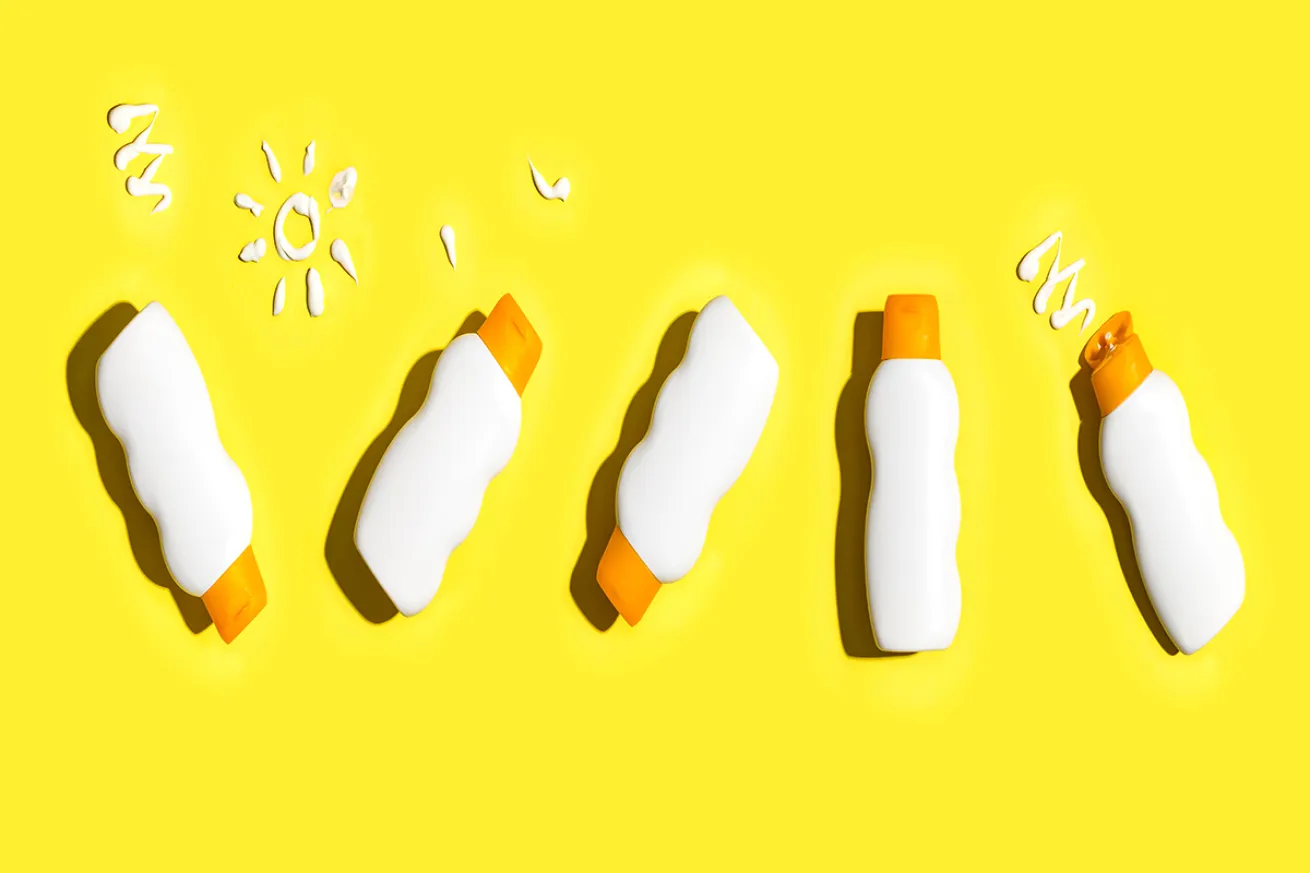 Sunscreen bottles against bright yellow background.