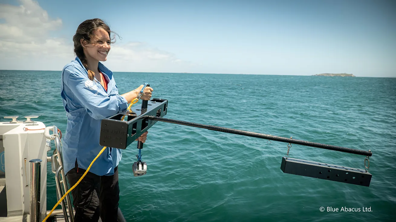 Woman holds a camera over the edge of the boat.