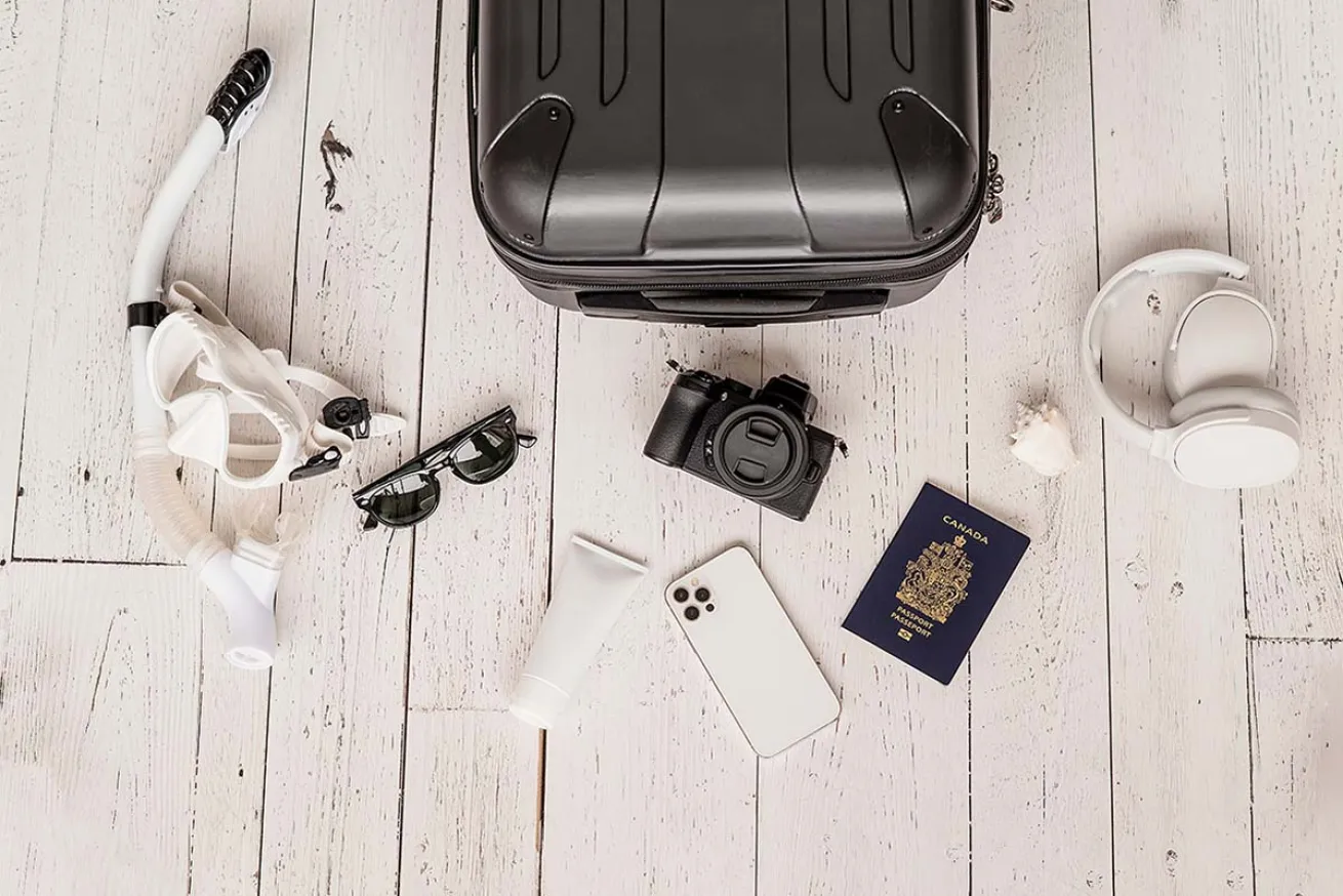 Suitcase surrounded by travel paraphernalia and a mask with snorkel