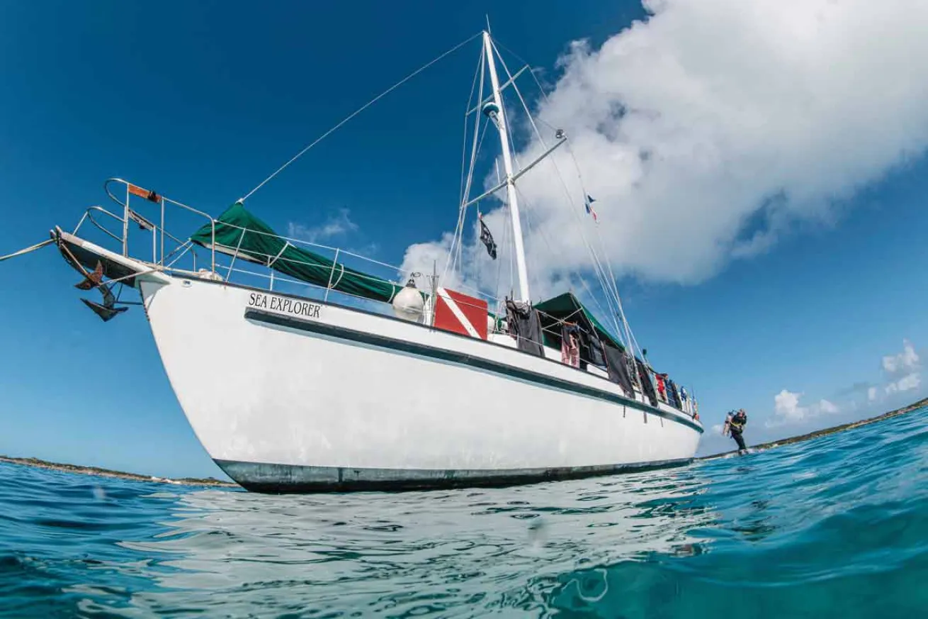 a boat sailing over water with a diver jumping off the back