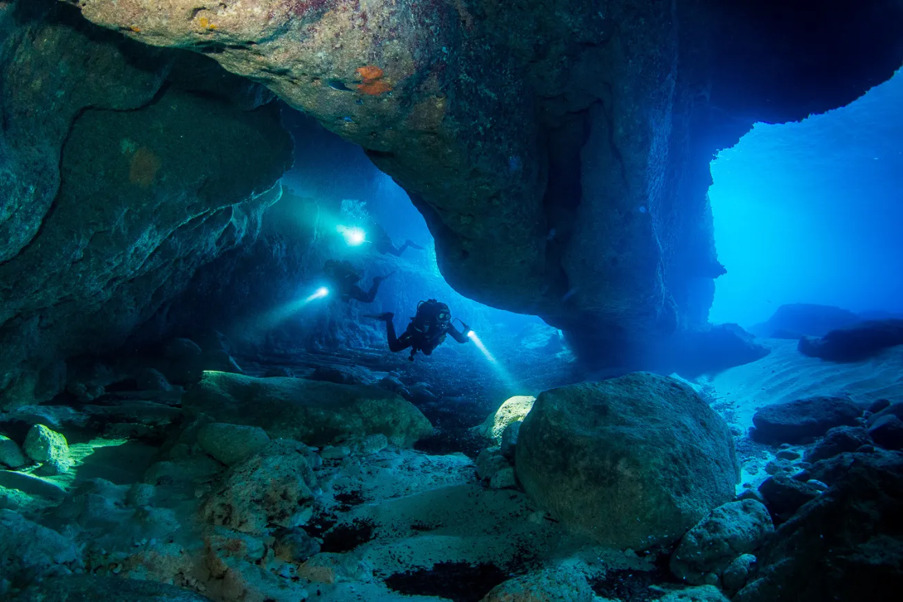 Scuba divers under a cave
