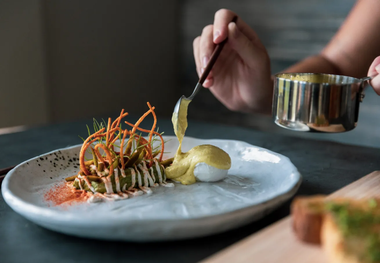 A person holding a spoon over a plate of food