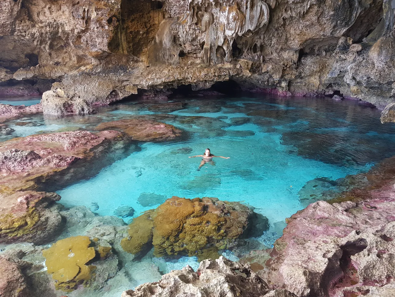 a person swimming in a crystal clear rock pool