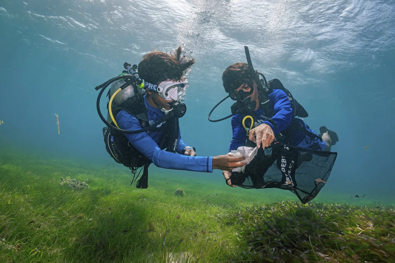 Divers help clear debris from the seafloor.