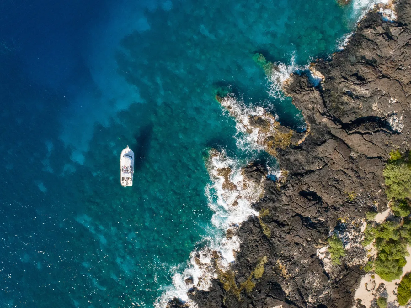 Dive boat cruising the clear blue waters of Hawaii’s Big Island, ready to take divers to top underwater sites.