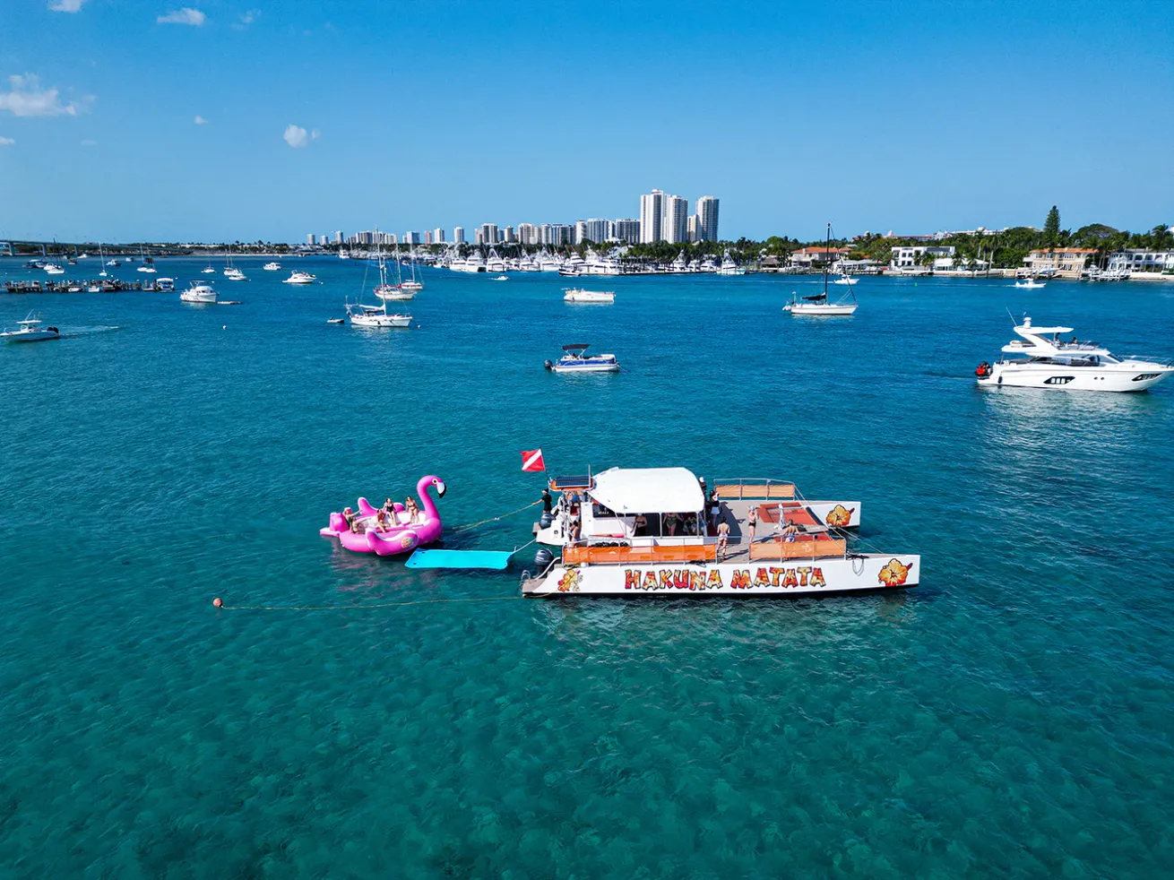catamaran on clear ocean water with giant flamingo float in back