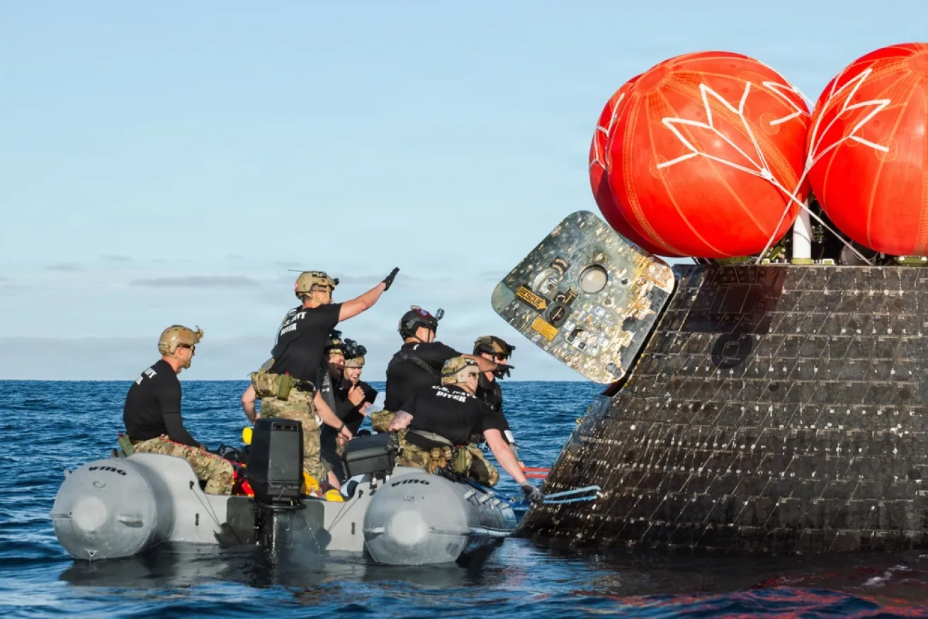 U.S. Navy divers approach the Artemis II crew module to retrieve the crew and spacecraft following their return to Earth and splashdown in the Pacific Ocean.