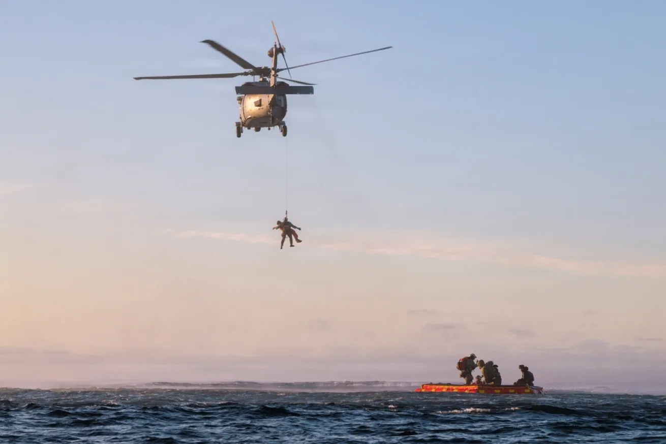 A U.S. Navy aircrewman hoists an astronaut to a helicopter after their return from the Artemis II lunar mission. 