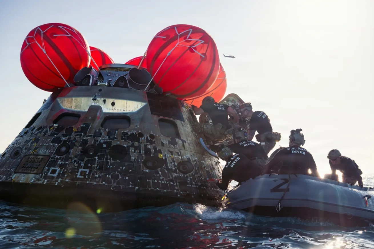U.S. Navy divers enter the Artemis II crew module to recover the crew after returning from their lunar mission.