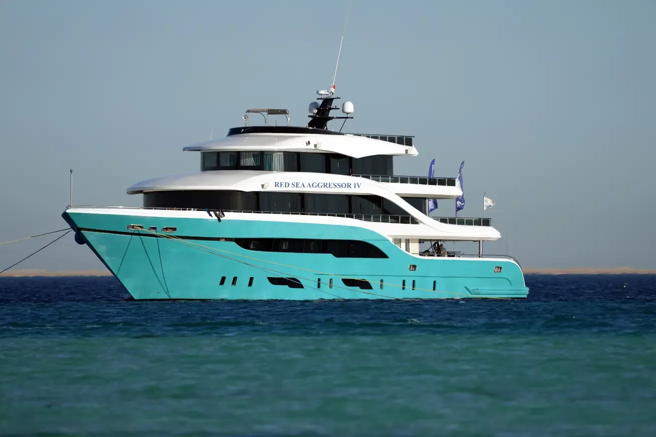 Photograph of a large multi-deck boat named Red Sea Aggressor IV on calm water under.