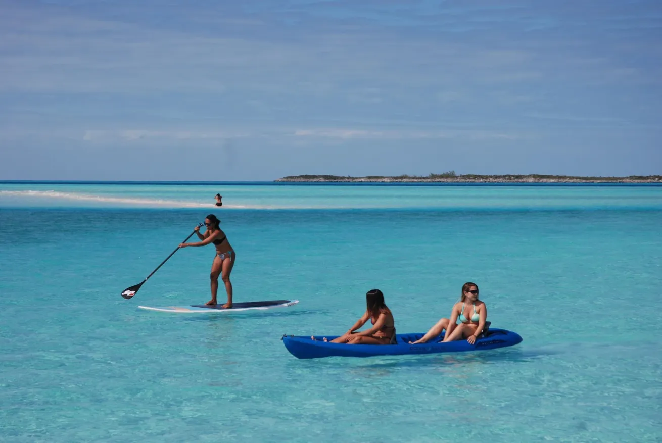 Guests paddleboarding and kayaking in calm turquoise water during an All Star Liveaboards Bahamas liveaboard trip
