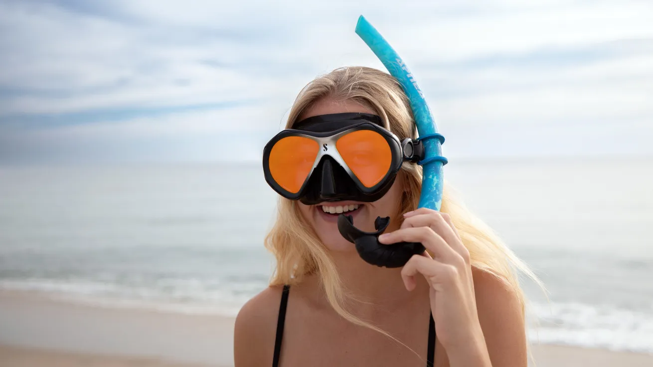 a woman with snorkeling gear on at the beach