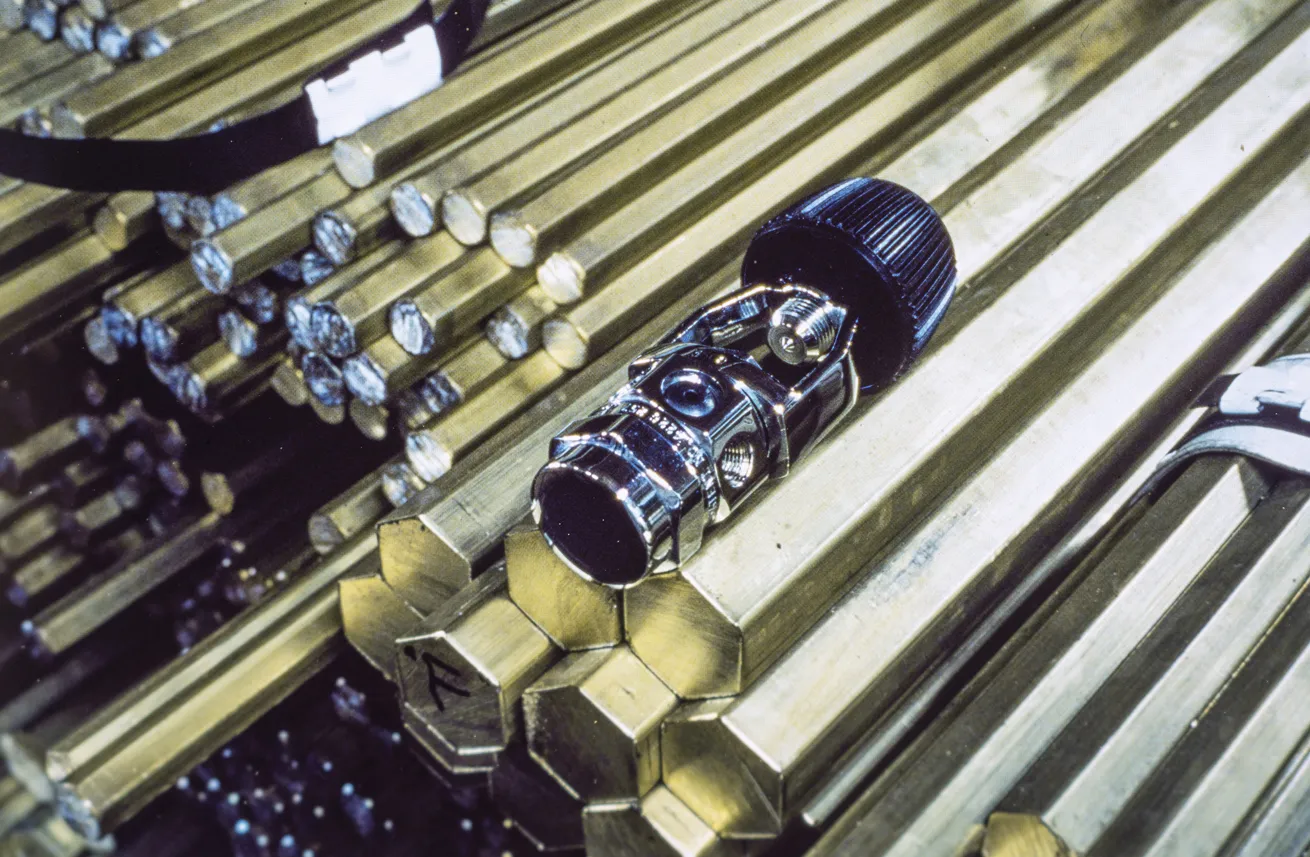 A regulator first stage produced in the early ’80s. The brass rods beneath are the raw material used for production.
