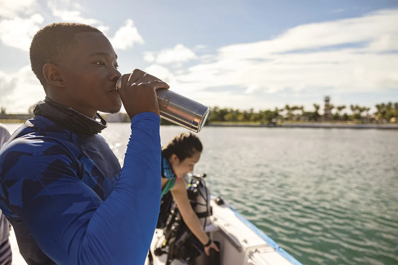a diver drinks out of a reusable water bottle on a dive boat 