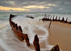 Ship wreckage sticks out of beach sand