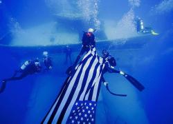 Divers carrying flag near shipwreck