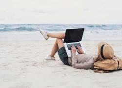 Woman uses laptop on beach
